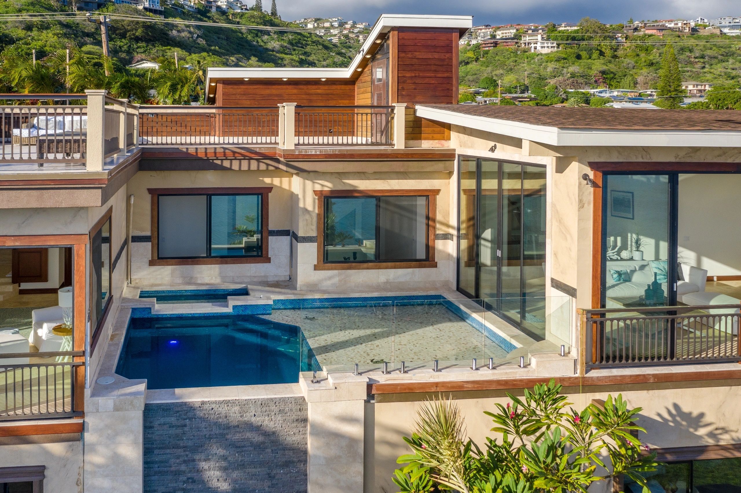 Completed custom home with wood balconies and glass-railed pool deck